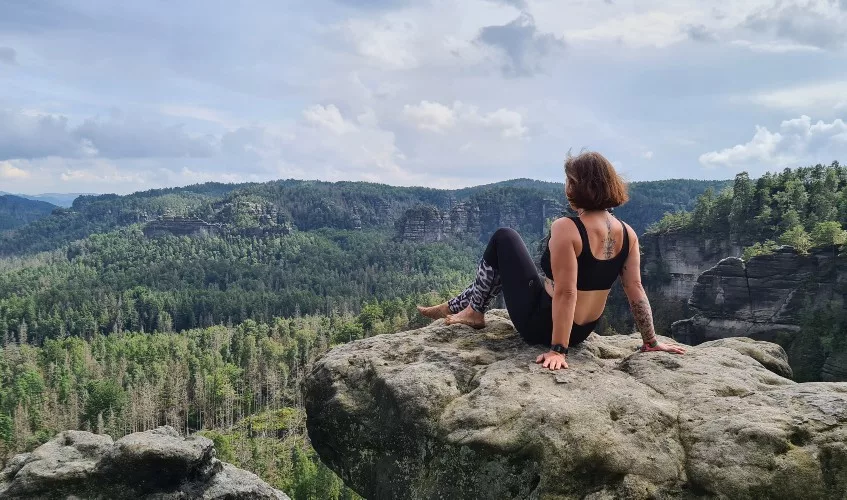 Mindfulnesstrainer Jennifer Olpen sitzt auf einem Fels und blickt in die Ferne, sie denkt darüber nach, wie man Resilienz stärken kann.